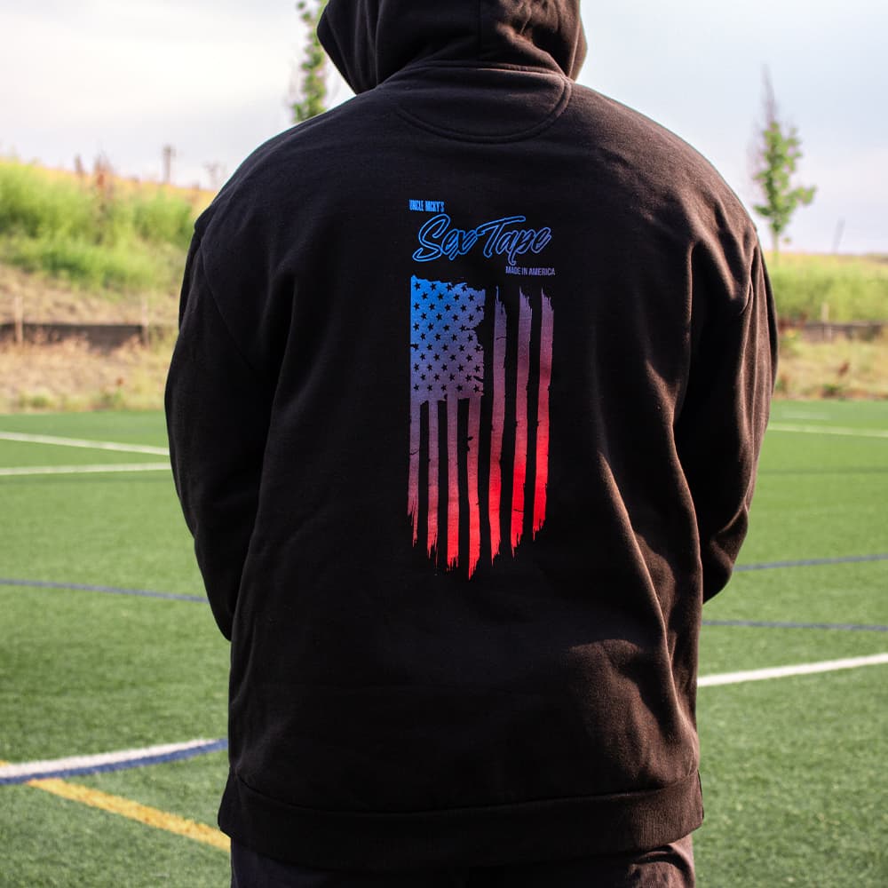 Man wearing black Uncle Nicky's Sex Tape hoodie with blue-to-red distressed American flag graphic on the back