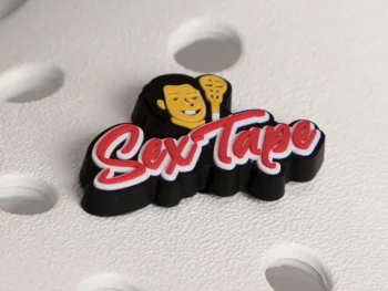 Close-up of Uncle Nicky’s Sex Tape lacrosse shoe charm attached to a white foam slide, featuring a 3D logo with mascot and red script lettering